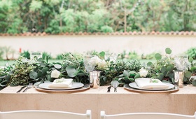 Lush Foliage Table Décor
Photography: Lucas Rossi and Michelle Kyle
Read More:
http://www.insideweddings.com/weddings/inspirational-outdoor-garden-wedding-shoot-with-modern-elements/687/ Garden wedding reception table with greenery runner, white roses, golden tablecloth, silver tumblers