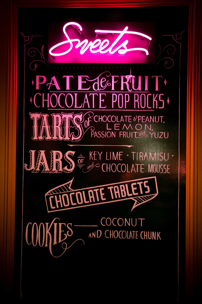 chalkboard with neon sign displaying sweets at dessert bar