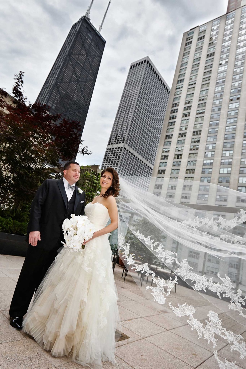 Bride with Flowing Veil and Groom in Chicago
Photography: KingenSmith
Read More:
http://www.insideweddings.com/weddings/delicately-detailed-chicago-wedding-with-jewish-christian-customs/762/ bride and groom stand in chicago bride's vera wang veil flowing in the wind white orchid bouquet