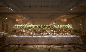 Long White Tablescape, Tall Connecting Arrangements
Photography: Eli Turner Studios
Read More:
http://www.insideweddings.com/weddings/ballroom-wedding-with-unique-garden-elements-in-washington-dc/819/ a long table with a white linen featuring tall white-and-green arrangements connected ghost chairs