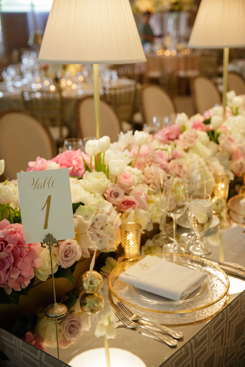 Table Number in Gold Calligraphy
Photography: Karlisch Studio
Read More:
http://www.insideweddings.com/weddings/southern-chic-wedding-in-oklahoma-with-performance-by-boyz-ii-men/697/ Wedding reception table with a mirror top, table number written in gold ink, white roses, tulips,