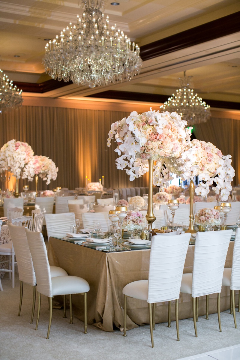 Covered White Chairs and Chandeliers
Photography: Jessica Claire Photography
Read More:
http://www.insideweddings.com/weddings/traditional-armenian-ceremony-luxurious-ballroom-reception/1006/ white covers on chiavari chairs, gold stands and floral arrangements orchids blush roses chandeliers