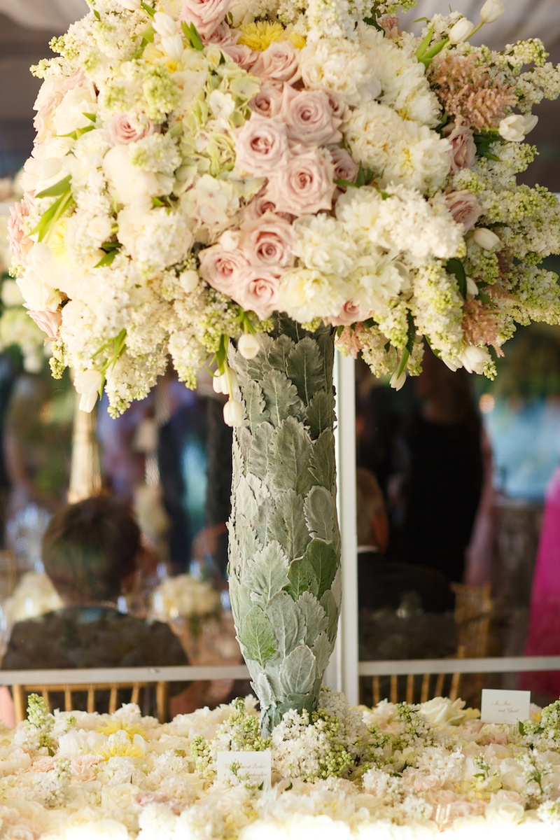 Pastel Arrangement in Unique Vase
Photography: Karlisch Studio
Read More:
http://www.insideweddings.com/weddings/southern-chic-wedding-in-oklahoma-with-performance-by-boyz-ii-men/697/ Wedding escort card table covered in flowers, vase covered in leaves with pink roses, white peonies