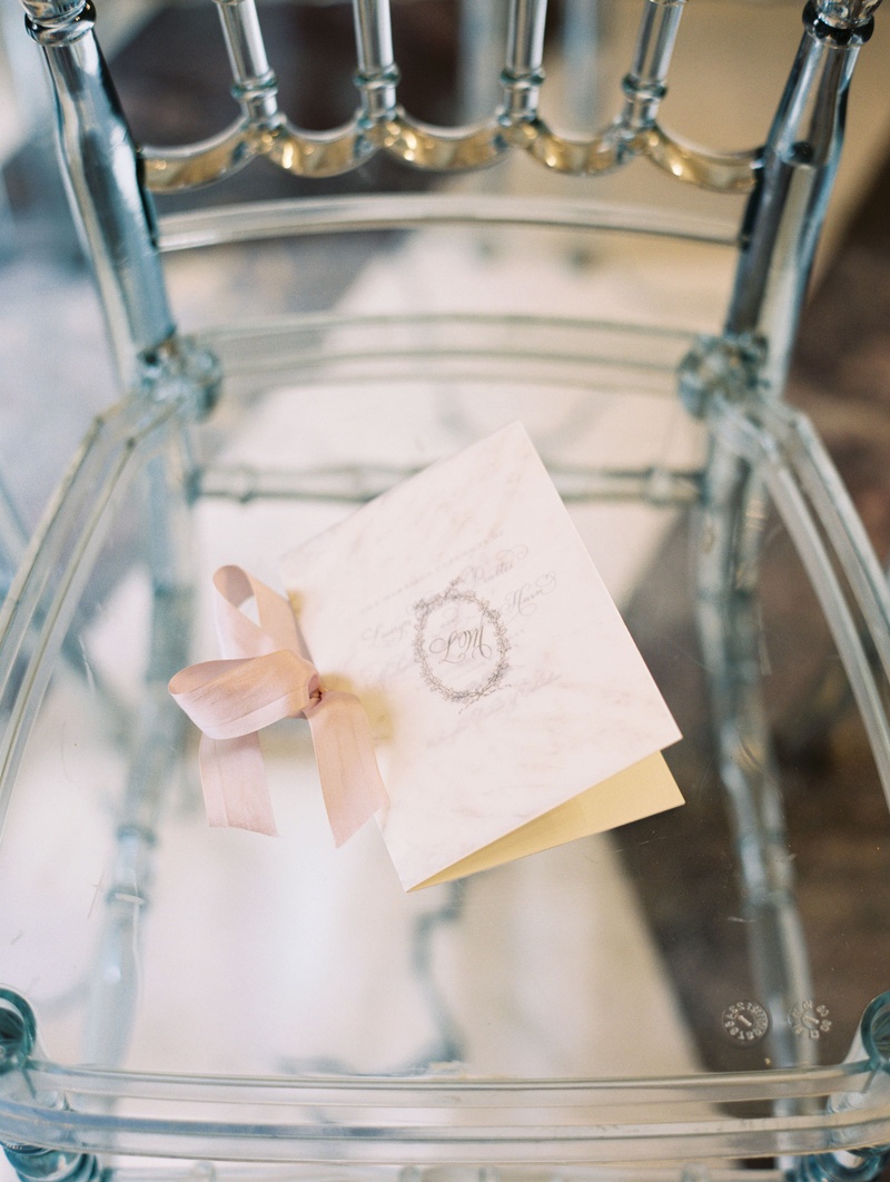 Chic Parisian-Inspired Ceremony Program
Photography: Abby Jiu Photography
Read More:
http://www.insideweddings.com/weddings/chic-parisian-romance-inspired-spring-wedding-in-washington-dc/1038/ Clear chiavari chair with ceremony program on seat pink ribbon monogram on front oval shape
