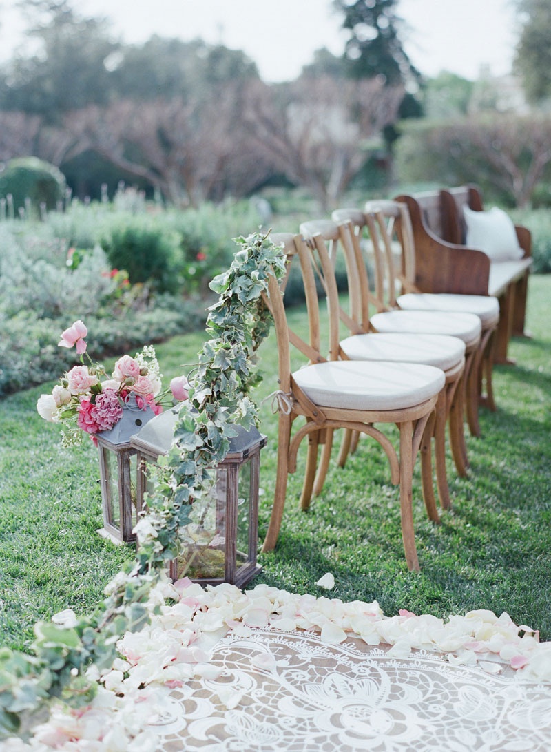 Lace-Inspired Aisle at Alfresco Ceremony
Photography: Elizabeth Messina
Read More:
http://www.insideweddings.com/weddings/fairy-tale-wedding-with-enchanted-forest-theme-in-santa-barbara/778/ White lace laser cut aisle runner with flower petal garland wood chairs with white cushions, lantern