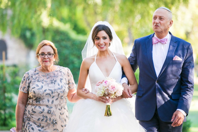Bride's Parents Walk Her Down the Aisle
Photography: Callaway Gable
Read More:
http://www.insideweddings.com/weddings/alfresco-summer-wedding-with-lush-foliage-accents-in-california/805/ a bride in a tulle ball gown holding a blush and ivory bouquet walks down aisle escorted parents