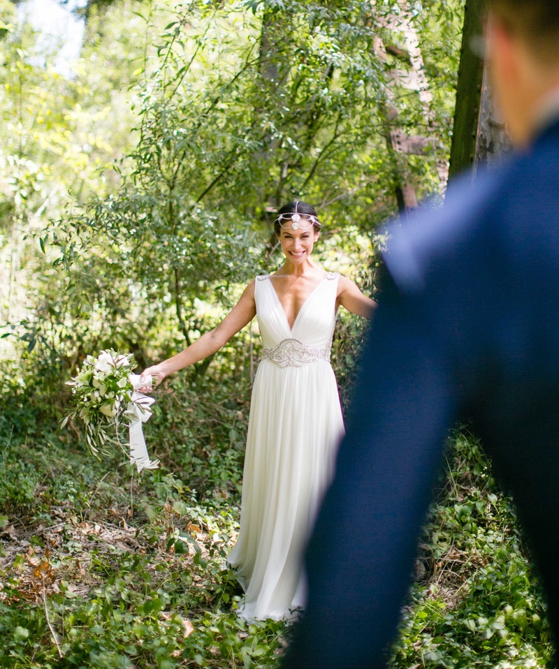 Bride with Open Arms During "First Look"
Photography: Samuel Lippke Studios
Read More:
http://www.insideweddings.com/weddings/a-rustic-camp-themed-outdoor-wedding/908/ Back of groom's navy blue suit walking toward bride in forest v-neck wedding dress first look