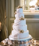 Cake with Gold Roses and Accent Roping
Photography: Eli Turner Studios
Read More:
http://www.insideweddings.com/weddings/elegant-and-romantic-jewish-ballroom-wedding-in-washington-dc/1109/ five-tiered wedding cake with fondant drapery and rope accents with golden flowers
