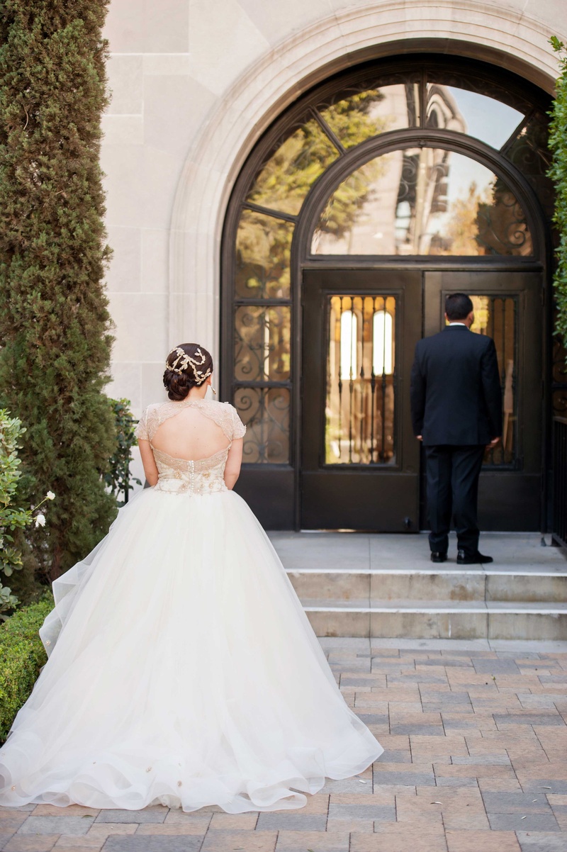 Bride in Golden Ball Gown During First Look
Photography: KLK Photography
Read More:
http://www.insideweddings.com/weddings/greek-orthodox-church-ceremony-glamorous-purple-gold-reception/730/ Back of bride in Lazaro wedding dress waiting for groom during First Look at wedding