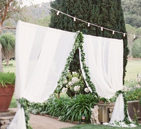 Sheer White Curtain Lined with Foliage
Photography: Lane Dittoe Photography
Read More:
http://www.insideweddings.com/weddings/charming-wedding-at-california-estate-inspired-by-european-villa/817/ sheer white curtain entrance to outdoor reception space lined with foliage below string of lights
