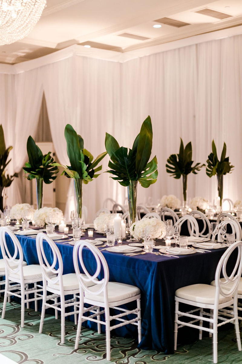 Tropical Large Palm Centerpieces
Photography: Valorie Darling Photography
Read More:
http://www.insideweddings.com/weddings/santa-monica-wedding-with-tropical-touches-east-coast-inspiration/1232/ wedding reception long table navy blue linen white chair white flowers tall greenery tropical palms