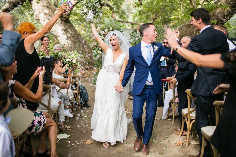 Bubble Toss at Outdoor Ceremony
Photography: Samuel Lippke Studios
Read More:
http://www.insideweddings.com/weddings/a-rustic-camp-themed-outdoor-wedding/908/ Bride in Jenny Packham wedding dress and groom in navy blue suit hold hands up wedding ceremony
