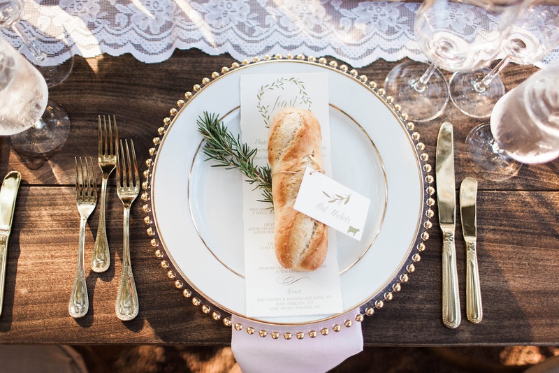 Baguette on Top of Wedding Menu
Photography: Katie Shuler Photography
Read More:
http://www.insideweddings.com/weddings/rustic-chic-outdoor-wedding-at-a-winery-in-northern-california/945/ French Baguette with place card on top of wedding menu and rosemary wood table lace runner gold