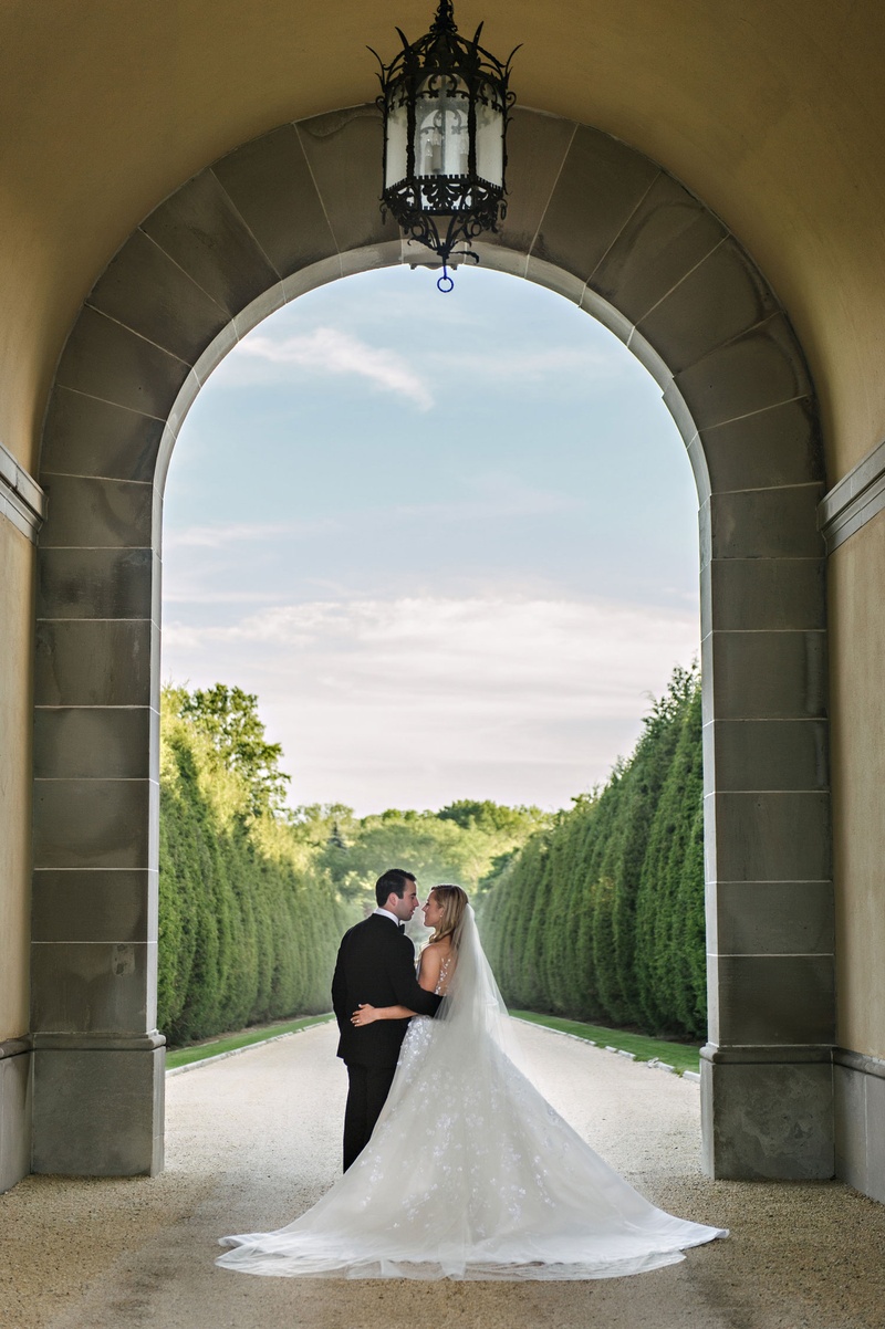 Gorgeous Couple's Portrait at Oheka Castle
Photography: Dear Stacey
Read More:
http://www.insideweddings.com/weddings/sentimental-alfresco-ceremony-classic-reception-at-oheka-castle/1016/ Bride and groom under tall archway at Oheka Castle gardens cyprus trees clouds sky