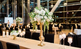 Tall Centerpiece on Long Table
Photography: Erin Wilson Photography
Read More:
http://www.insideweddings.com/weddings/timeless-wedding-with-white-black-and-gold-palette-in-little-rock/993/ tall centerpiece with white hydrangeas, greenery and amaranths, gold base, long table