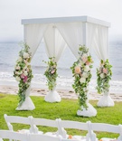 Four-Post Structure with Flowers
Photography: Willa Kveta Photography
Read More:
http://www.insideweddings.com/weddings/alfresco-ceremony-by-the-beach-elegant-barn-wedding-reception/1298/ wedding ceremony on grass lawn by beach ocean white drapery greenery peach pink flowers dahlia rose