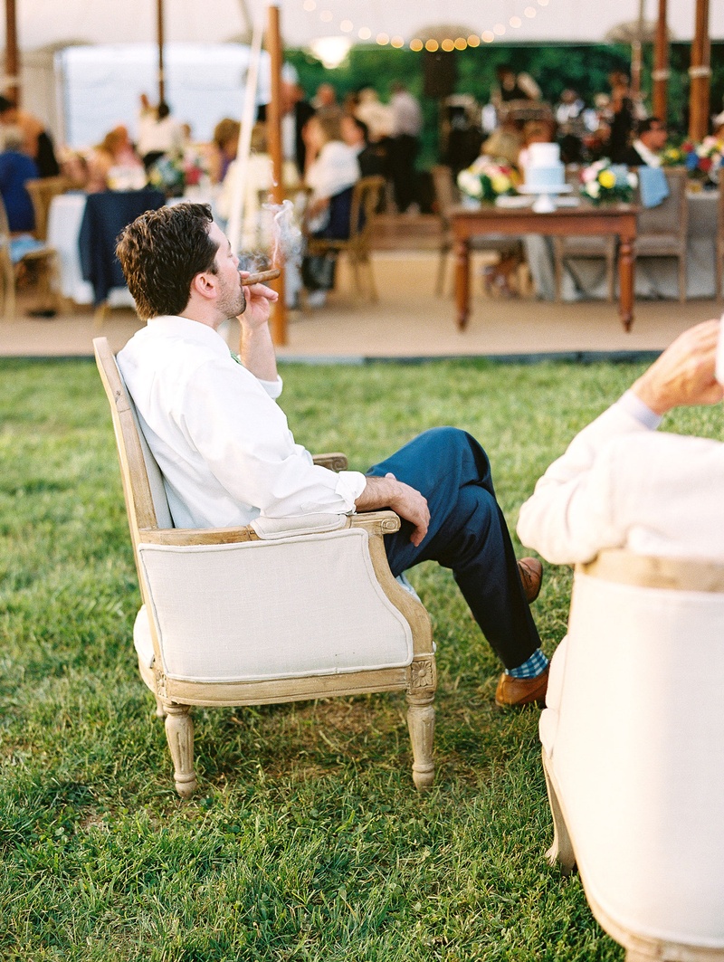 Guest Enjoying Cigar in Armchair
Photography: Bonnie Sen Photography
Read More:
http://www.insideweddings.com/weddings/outdoor-ceremony-tented-reception-by-a-tranquil-river-in-maryland/1088/ Male guest having cigar at cigar station lounge area by tent wedding reception