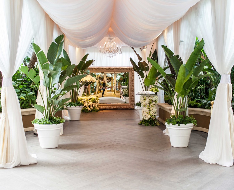 Tropical Details at Beverly Hills Venue
Photography: Samuel Lippke Studios
Read More:
http://www.insideweddings.com/weddings/romantic-jewish-wedding-with-lush-ivory-flowers-rose-gold-details/790/ Wedding walkway gold mirror with hashtag, tropical leaves, white drapery