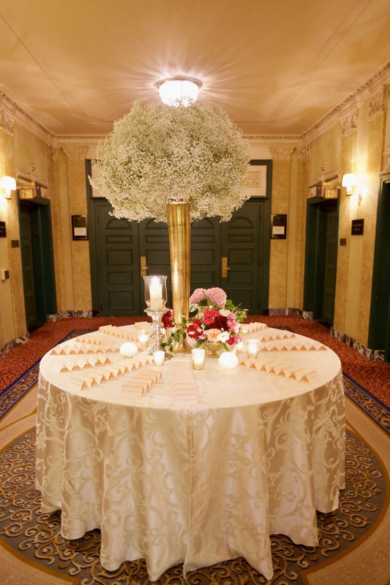 Escort Card Table with Baby's Breath
Photography: Amanda Sudimack for Artisan Events
Read More:
http://www.insideweddings.com/weddings/customized-chicago-wedding-with-pink-blush-marsala-color-palette/911/ Tall gold vase on round escort card table filled with baby's breath and pink flower arrangements