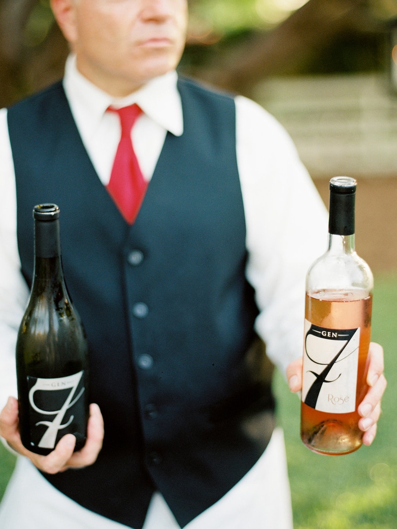 Server in Red Tie Holds Two Wine Bottles
Photography: Ryan Ray Photography
Read More:
http://www.insideweddings.com/weddings/outdoor-wedding-with-vibrant-pink-orange-decor-in-california/723/ Gen7 Rose and wine in bottles held by wedding catering server