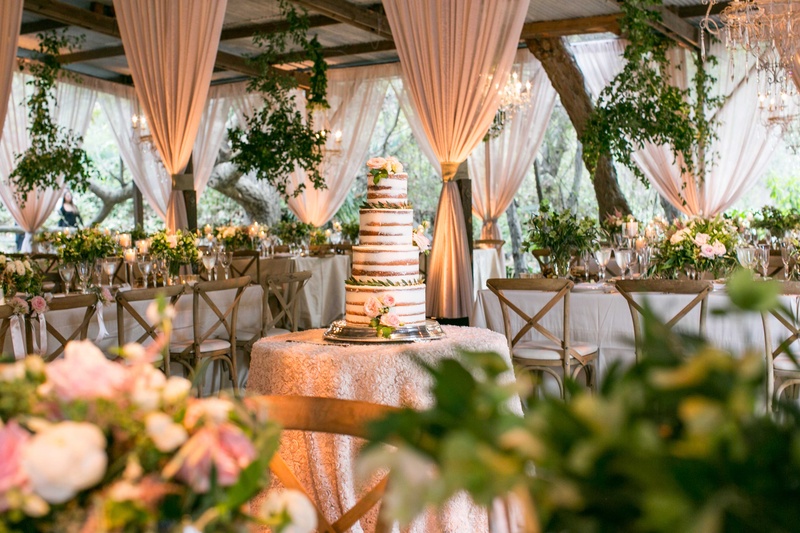 "Naked" Cake in Center of Barn
Photography: Samuel Lippke Studios
Read More:
http://www.insideweddings.com/weddings/a-rustic-camp-themed-outdoor-wedding/908/ Naked cake with fresh flowers in center of barn venue blush drapery chandeliers foliage