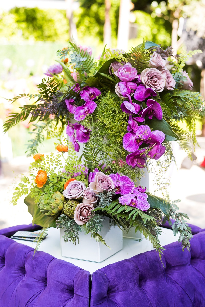Cocktail Hour Unique Floral Arrangement
Photography: Callaway Gable
Read More:
http://www.insideweddings.com/weddings/modern-in-the-round-ceremony-whimsical-garden-inspired-reception/1155/ Wedding cocktail hour bright purple tufted settee furniture orchid rose greenery artichoke flowers