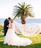 Newlyweds Kiss While Veil Blows in Wind
Photography: Brian Leahy Photography
Read More:
http://www.insideweddings.com/weddings/beachy-southern-california-ceremony-winter-wonderland-reception/877/ Bride in Demetrios, groom in Ermenegildo Zegna kiss on grass ocean view
