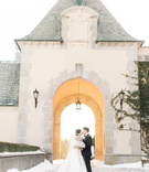 Couple at Oheka Castle Winter Wedding
Photography: Lauren Fair Photography
Read More:
http://www.insideweddings.com/weddings/elegant-wedding-with-muted-regal-decor-at-oheka-castle-in-new-york/1243/ bride in ball gown with white fur wrap veil low bun kiss groom in arch of oheka castle snow ground