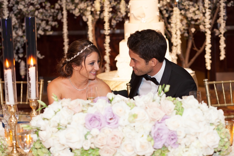 Bride %26 Groom at Floral Head Table
Photography: Jay Lawrence Goldman Photography
Read More:
http://www.insideweddings.com/weddings/elegant-white-lavender-ballroom-wedding-with-cherry-blossom-trees/710/ Bride with a crystal headband stares at groom in black tuxedo at head table with white & purple rose