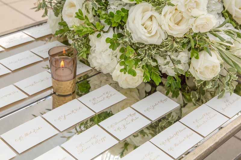 Gold Calligraphy Escort Cards on Mirror
Photography: Carasco Photography
Read More:
http://www.insideweddings.com/weddings/traditional-ceremony-glamorous-garden-inspired-tented-reception/943/ Mirror tabletop with gold calligraphy white escort cards white rose flower arrangement greenery
