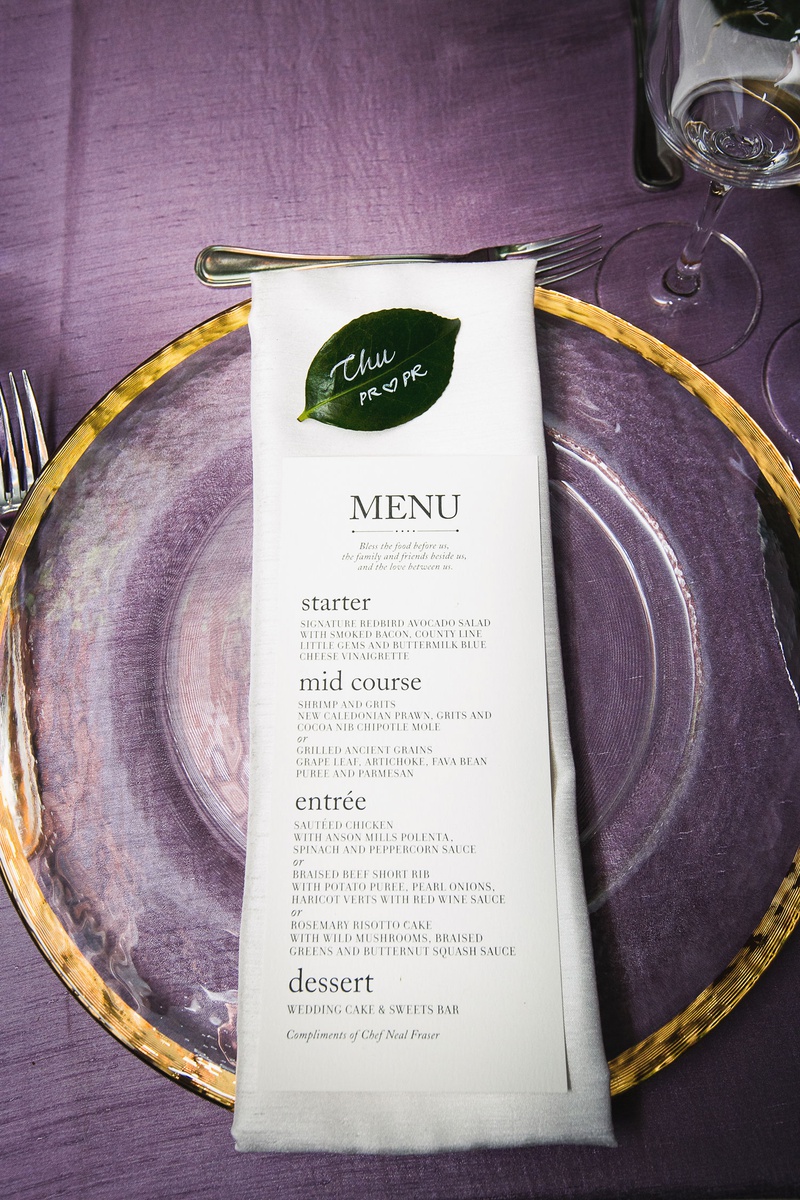 White Menu on Top of Charger Plate
Photography: Callaway Gable
Read More:
http://www.insideweddings.com/weddings/modern-in-the-round-ceremony-whimsical-garden-inspired-reception/1155/ wedding menu on top of linen napkin clear gold charger green leaf place card purple linens