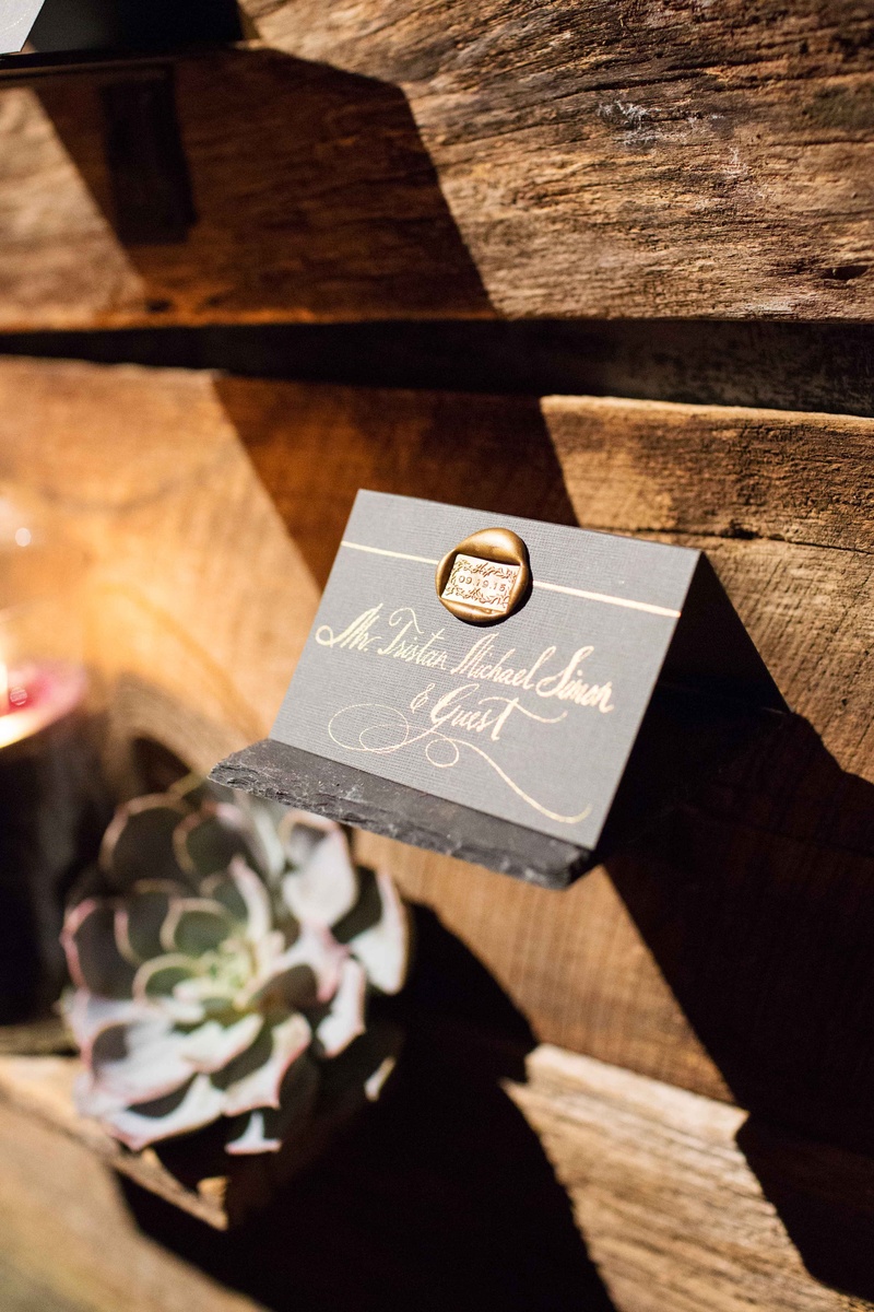 Grey Escort Card with Wax Seal
Photography: Perez Photography
Read More:
http://www.insideweddings.com/weddings/incredible-tented-ceremony-barn-reception-at-ranch-in-aspen/860/ Grey escort card with gold calligraphy and wax seal on barn wood wall at rustic reception