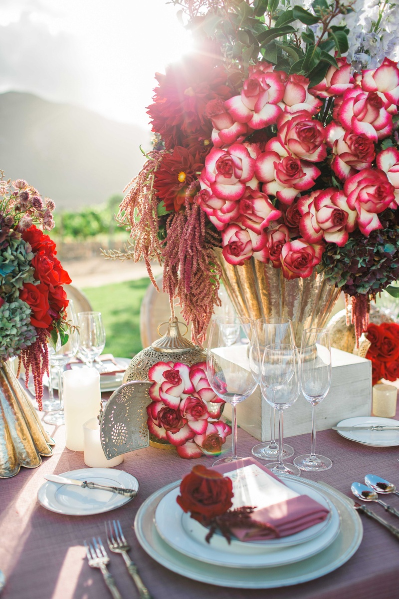 Lush and Rustic Floral Arrangements on Vineyard Table
Photography: Jenny Quicksall Photography
Read More:
http://www.insideweddings.com/weddings/romantic-wedding-shoot-for-valentines-day-at-california-vineyard/751/ red and dark purple flowers floral arrangements in gold vases on pink table linens and lanterns