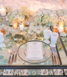 Crystals Dangling from Glass Table
Photography: Samuel Lippke Studios
Read More:
http://www.insideweddings.com/weddings/alfresco-ceremony-with-ocean-view-glamorous-tented-reception/1081/ Mirror table with crystals between layers white goblets ivory roses gold candle votives white goblet