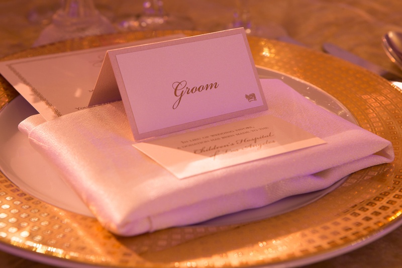 Elegant Place Card on Gold-Rimmed Charger
Photography: Jay Lawrence Goldman Photography
Read More:
http://www.insideweddings.com/weddings/elegant-white-lavender-ballroom-wedding-with-cherry-blossom-trees/710/ Wedding reception place setting with groom's place card, donation wedding favor card, white napkin