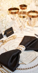 Black Bow-Inspired Napkin
Photography: KingenSmith
Read More:
http://www.insideweddings.com/weddings/elegant-vintage-inspired-destination-wedding-in-chicago/920/ Place setting with white table cloth, black napkin, gold flatware charger plate glassware bow detail