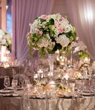 Clear Chairs Around Round Table
Photography: Karlisch Photography
Read More:
http://www.insideweddings.com/weddings/luxury-hotel-wedding-with-personalized-elements-in-dallas-texas/1119/ Tall centerpiece with white hydrangea green leaves pink white rose floating candles pink lighting