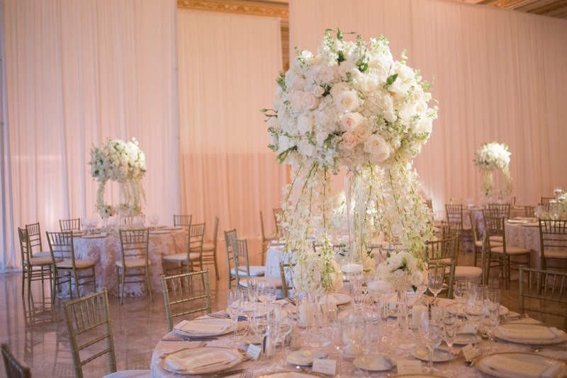 Tall Ivory Florals on Round Table
Photography: Nancy Cohn Photography
Read More:
http://www.insideweddings.com/weddings/destination-wedding-with-white-gold-color-palette-in-palm-beach/1028/ Wedding reception round table with tall centerpiece white flowers and cascading flowers to table