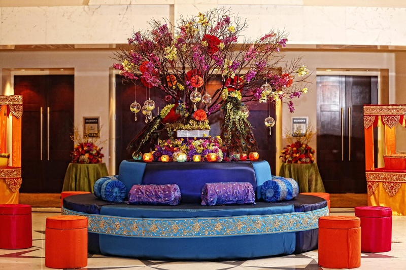 Colorful Seating
Photography: Tomas Ramos Photographers
Read More:
http://www.insideweddings.com/weddings/houston-indian-wedding-celebration-with-800-person-guest-list/435/ Round couch in royal blue with blue and purple cushions is topped with candles and color flowers