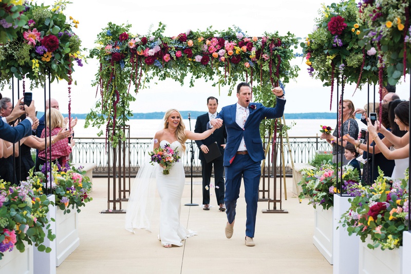 Celebrating Newlyweds
Photography: Kent Drake Photography
Read More:
http://www.insideweddings.com/weddings/bright-and-colorful-wedding-palette-with-ceremony-overlooking-lake/1315/ groom holding bride's hand and pumping fist after ceremony ending, with colorful florals