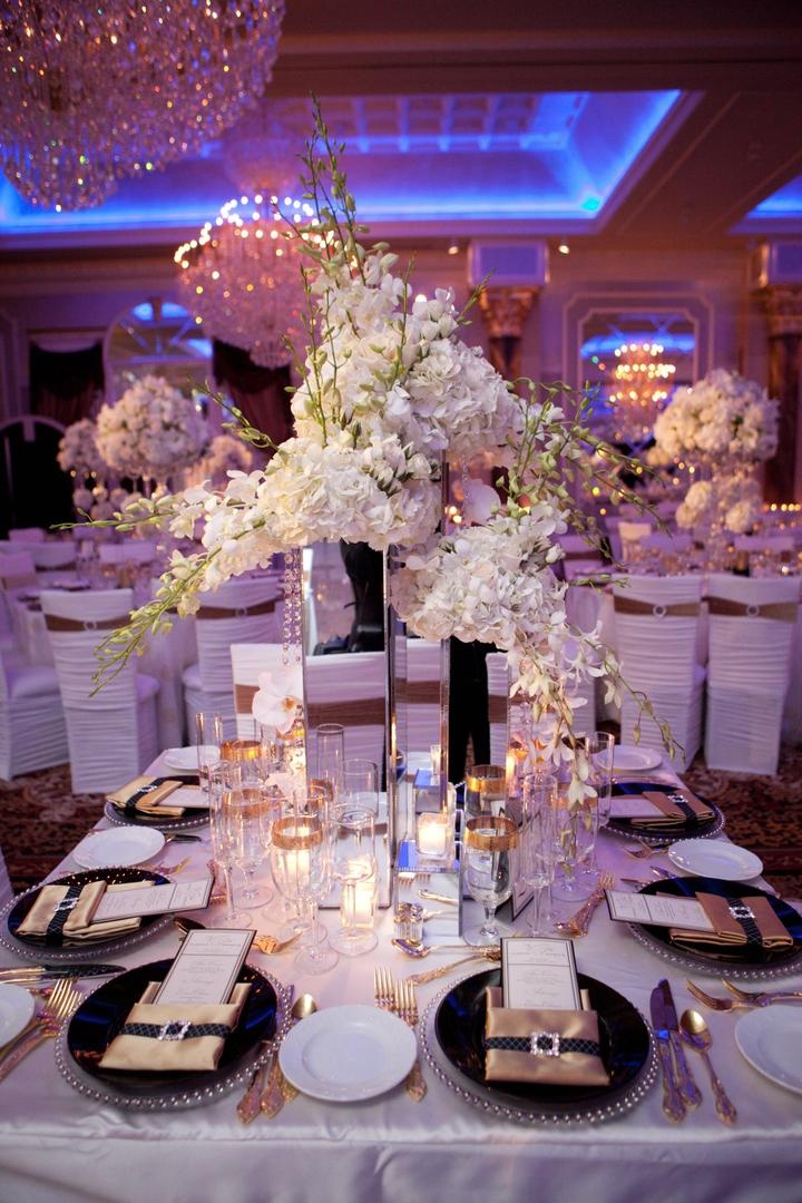 Table Decor
Photography: Josh Lynn Photography
Read More:
http://www.insideweddings.com/weddings/purple-white-gold-new-jersey-celebration/339/ Wedding reception table with tall mirrored vases and white flowers, silver beaded rimmed chargers