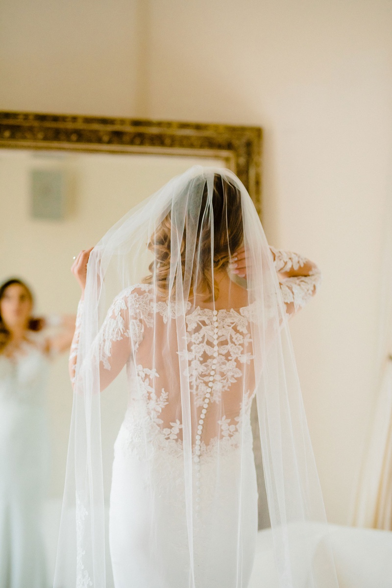 Bride Adjusting Veil
Photography: Kesha Lambert Photography
Read More:
http://www.insideweddings.com/weddings/personalized-ceremony-with-pink-florals-at-a-loft-in-new-york-city/1210/ bride in pronovias wedding dress with lace illusion back, long veil