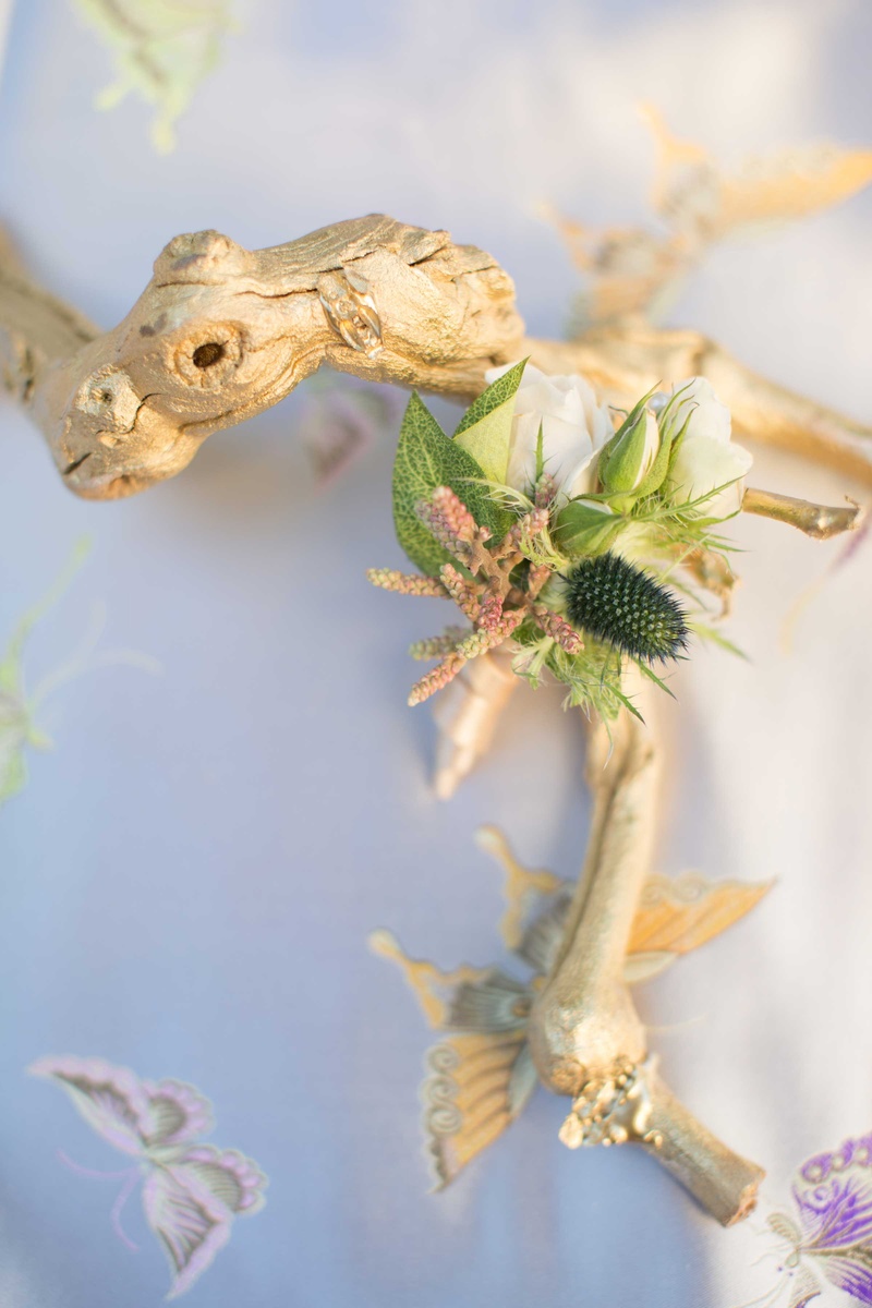 Golden Driftwood Topped with Boutonniere
Photography: Thisbe Grace Photography
Read More:
http://www.insideweddings.com/weddings/dramatic-wedding-shoot-inspired-by-alexander-mcqueen-chanel/749/ gold leaf driftwood on blue table linen with butterflies and small green boutonniere