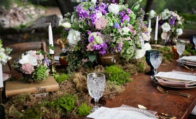 Floral Arrangement in Urn
Photography: Lucky Love Photography
Read More:
http://www.insideweddings.com/weddings/rustic-inspirational-wedding-shoot-in-a-forest-with-woodsy-details/661/ Outdoor wedding reception with wood table, moss runner, urn with white, purple, and green flowers
