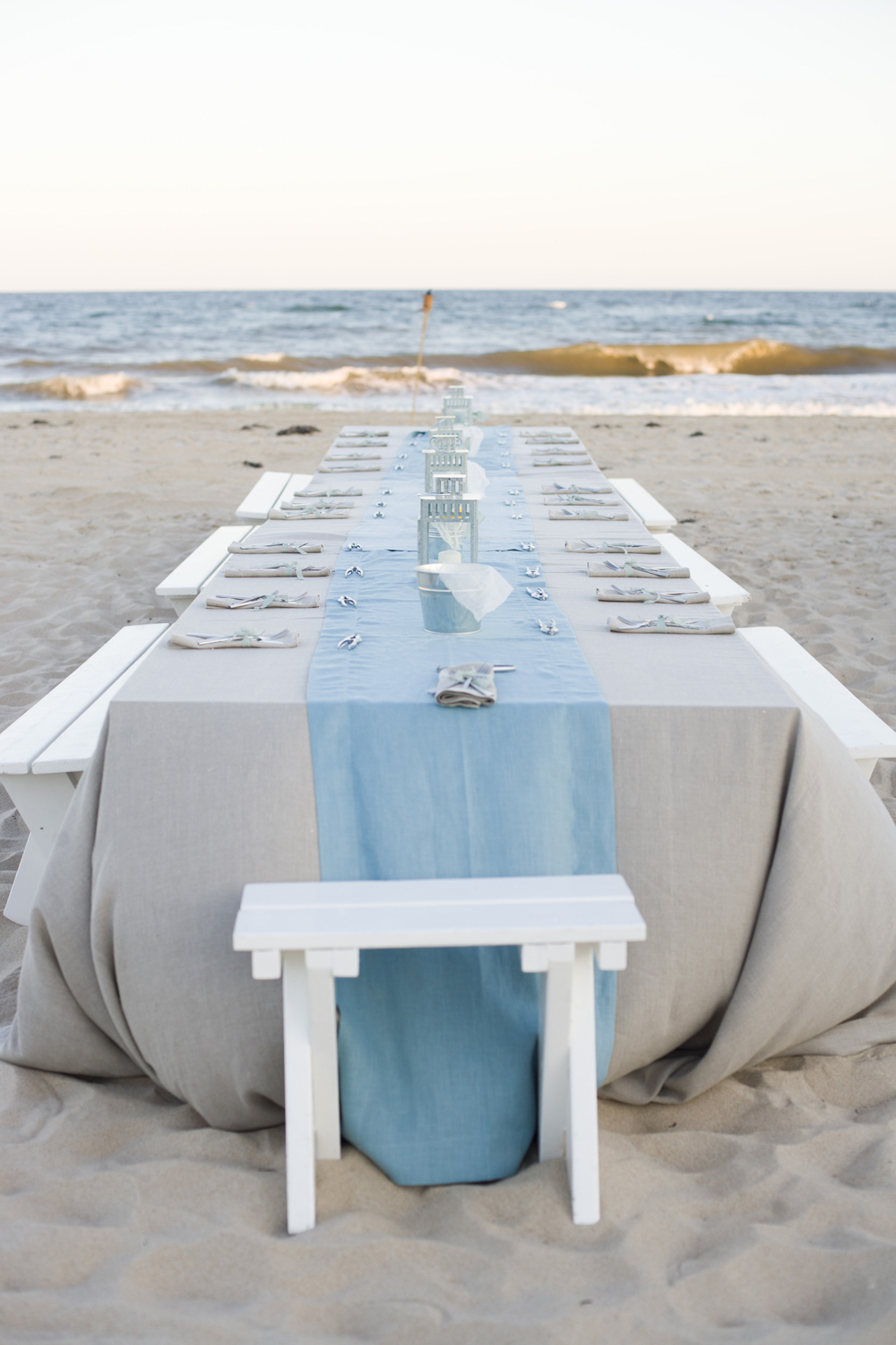 clam bake rehearsal dinner on the beach with blue runner white benches